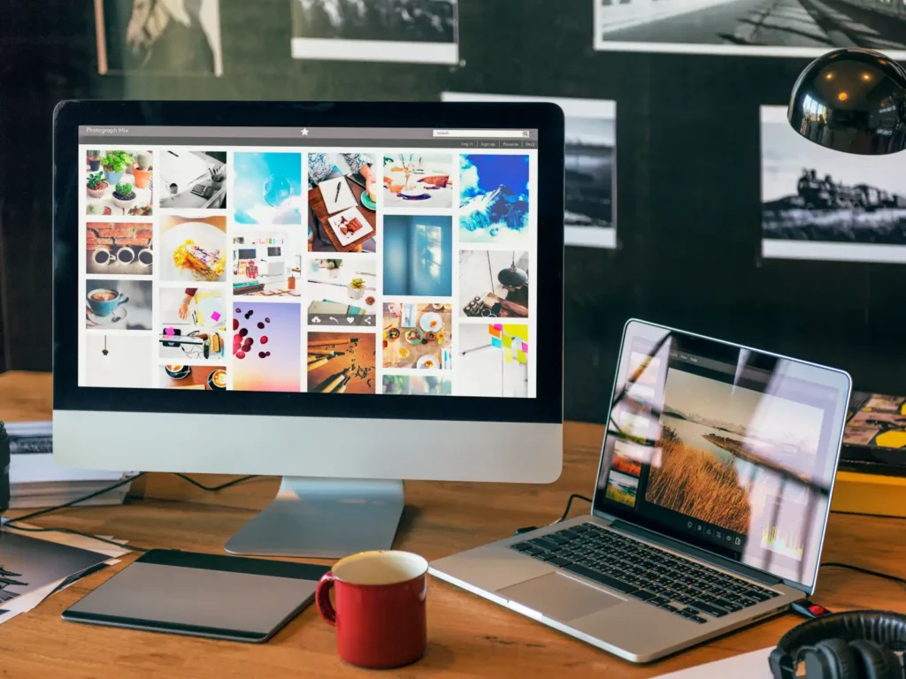 Content creator's desk with an iMac displaying a photo gallery and a laptop running an image editor