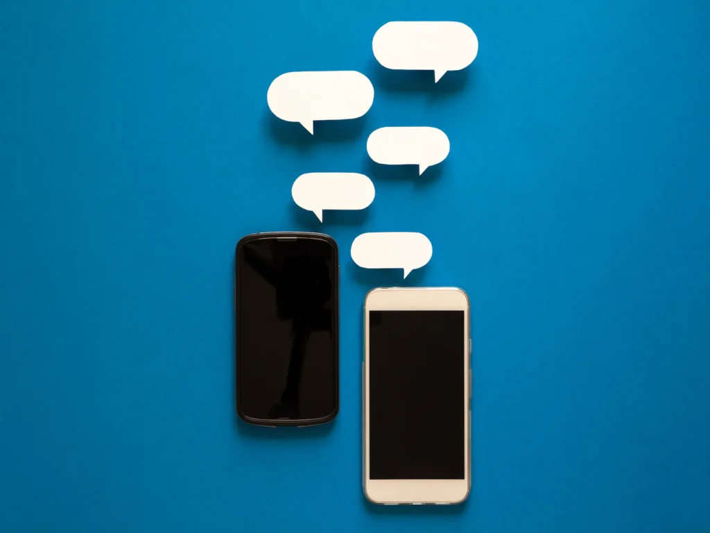 Two smartphones on a blue background with white conversation bubbles emerging from the screens